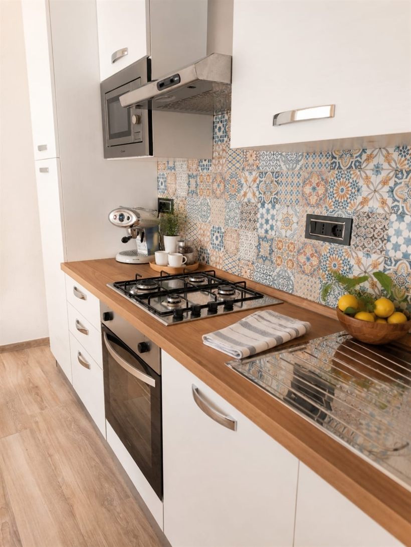 La cucina con piano in legno, piano cottura a gas e rivestimento a cementine colorate